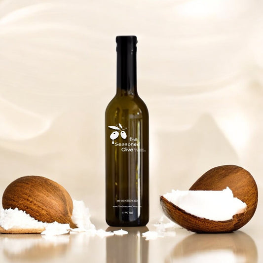 Elegant ivory cream background featuring whole coconuts with delicate coconut shavings and a small bowl of white balsamic vinegar in the foreground. A clean, sophisticated display showcasing the tropical essence of Coconut White Balsamic Vinegar